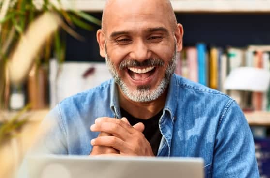 Man smiling while looking at a laptop